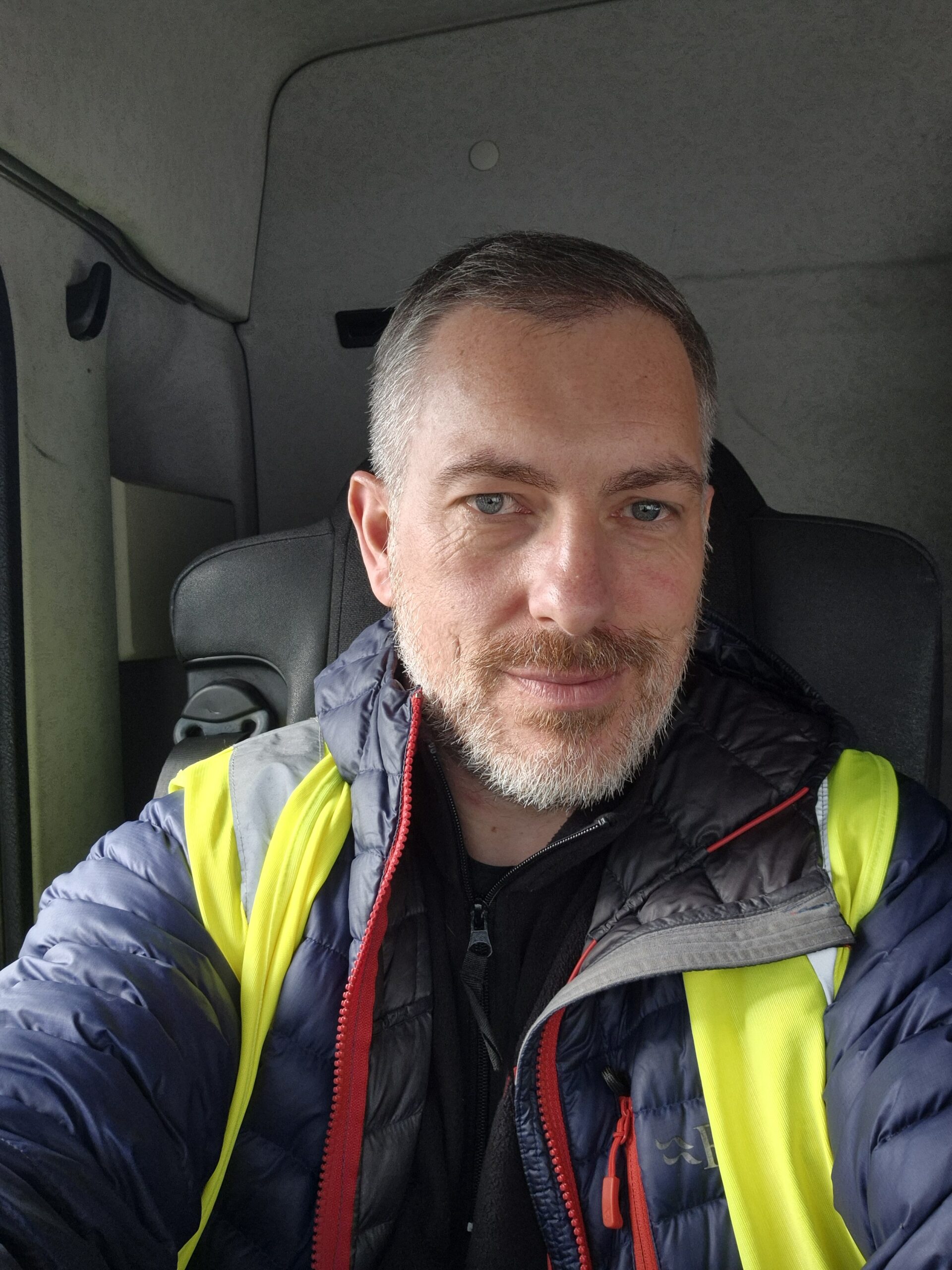 Simon Rowlands wearing high-vis workwear in a delivery van.